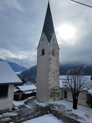 a church with a steeple in the snow at Ferienwohnung Biohof Untermar in Obervellach