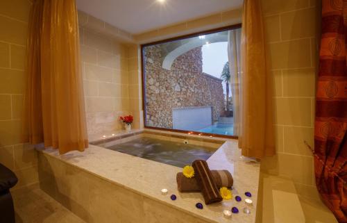 a bathroom with a tub with a large window at Carini Farmhouses in Għarb