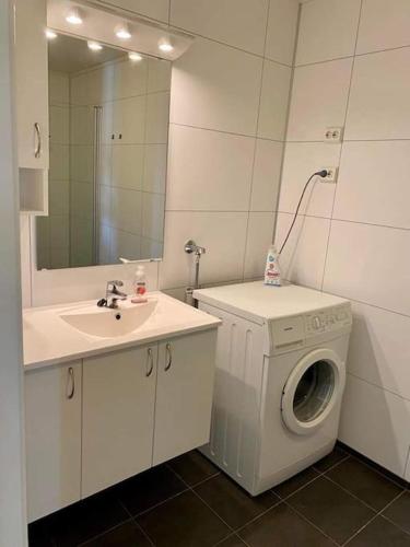 a bathroom with a washing machine and a sink at Leilighet sentralt på Senja in Silsand