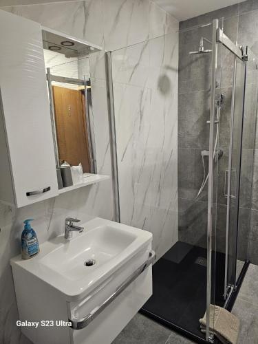 a white bathroom with a sink and a shower at Apartman Lavanda in Krapina