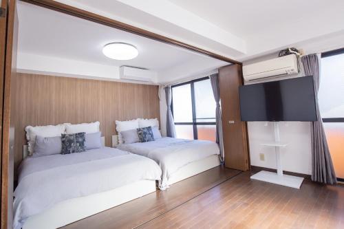 two beds in a room with a flat screen tv at Walk to Higashi-Nakano sta. COB3 in Tokyo