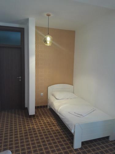 1 dormitorio con 1 cama blanca y 1 lámpara en Hotel PEKING, en Sarajevo