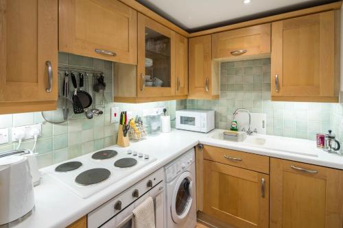 a kitchen with wooden cabinets and a stove top oven at 1BD Modern City Oasis: Near London Attractions in London
