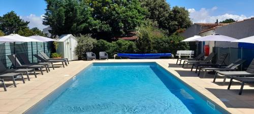 une grande piscine avec des chaises et une table dans l'établissement Logis Hôtel de la Plage, à La Cotinière