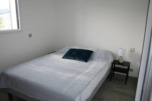 - un lit avec un oreiller bleu dans la chambre dans l'établissement maison sud Morbihan proche mer très calme, à Camoël