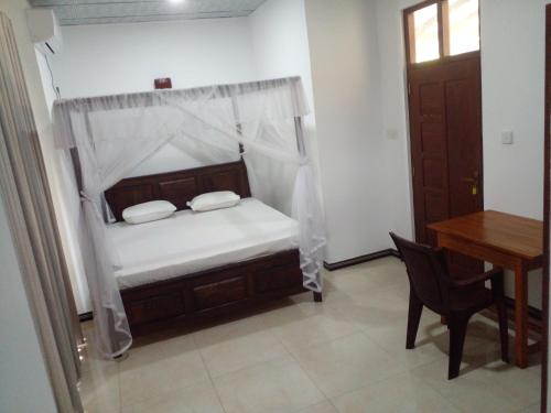 a small bedroom with a bed and a table at Amible Guest Home in Mirissa
