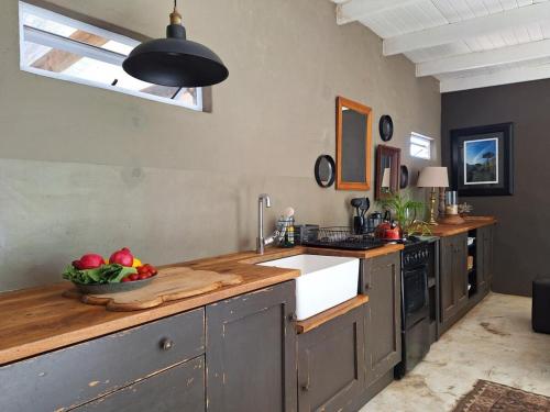 a kitchen with a sink and a bowl of fruit on a counter at Gelukkie in Paternoster
