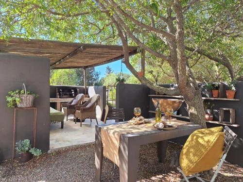 a patio with a table and chairs under a tree at Gelukkie in Paternoster