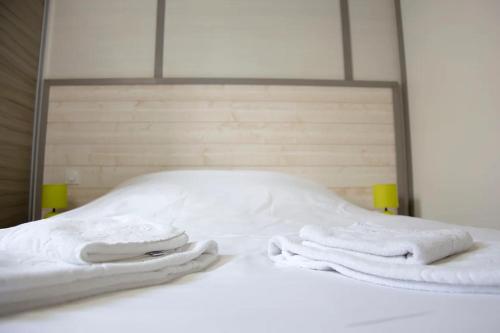two white towels sitting on top of a bed at Les Tourelles Village de vacances in Asnelles