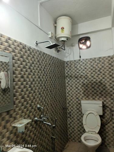 baño con aseo y una luz en el techo en Suryalaxmi guest house en Guwahati