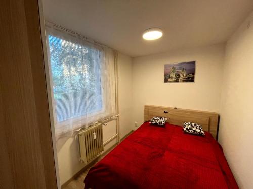 a bedroom with a red bed and a window at Útulný byt pro odpočinek i práci in Kutná Hora