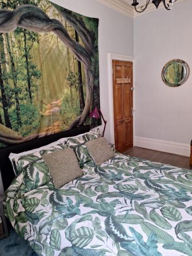a bedroom with a bed with a tree mural on the wall at Todmorden Bed & Breakfast - The Toothless Mog in Walsden