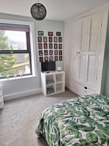 a bedroom with a bed and a window and a television at Todmorden Bed & Breakfast - The Toothless Mog in Walsden