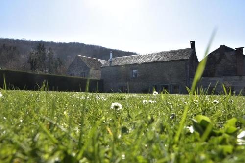 an old house with a field of grass in front of it at La Colline aux Fées in Yvoir