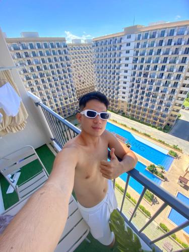 a man wearing sunglasses standing on the balcony of a hotel at RichAirbnb Cebu in Lapu Lapu City