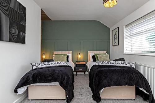 a bedroom with two beds with black and white covers at Tiger House - Driveway & Garden. Airport location! in Luton