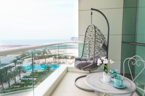 a room with a balcony with a swing and a table at Al Bateen Resdences by HAPPY SEASON JBR in Dubai