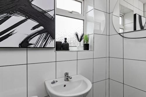 a white bathroom with a sink and a mirror at Tiger House - Driveway & Garden. Airport location! in Luton