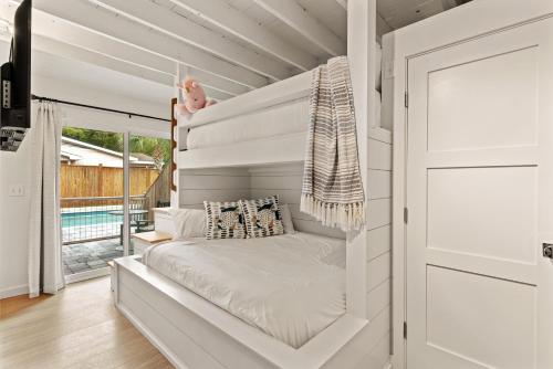 ein Bett in einem weißen Zimmer mit Veranda in der Unterkunft Perfect Symmetry - 520 Beach - 4 Bedrooms in Demere Park