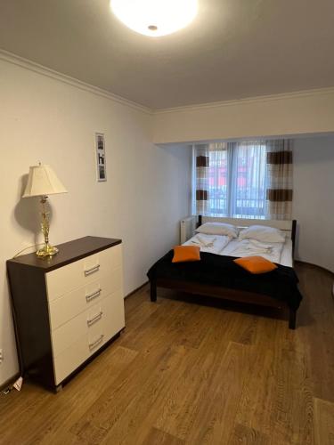 ein Schlafzimmer mit einem Bett, einer Kommode und einem Fenster in der Unterkunft Holiday Apartments in Krynica-Zdrój
