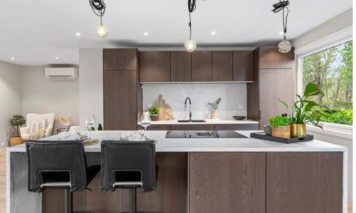 a kitchen with a sink and a counter with chairs at Tranquil Haven Villa in Ålesund