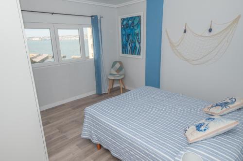 Schlafzimmer mit einem Bett mit blauen und weißen Streifen in der Unterkunft EL EMBARCADERO in Pedreña
