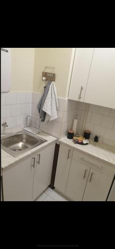 uma cozinha com armários brancos, um lavatório e um balcão em Apartman Ivan em Vršac