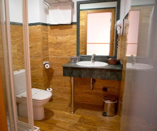 Un baño con lavabo, inodoro y espejo. en La Galerica, en Puerto de Mazarrón