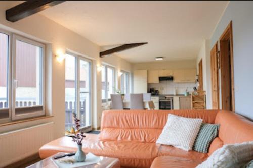 ein Wohnzimmer mit einem orangenen Sofa und einer Küche in der Unterkunft Ferienhaus Rudolph in Bad Schandau