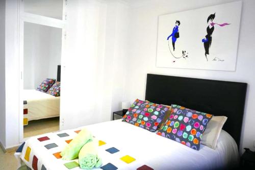 1 dormitorio con cama con colcha y almohadas blancas en Sol Centro Apartment B, en Sevilla