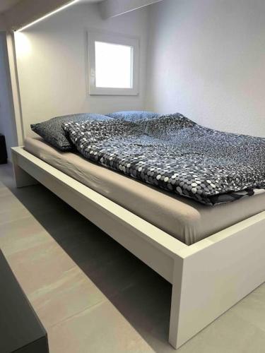 un lit dans une chambre blanche avec un cadre de lit dans l'établissement Neue Moderne Ferienwohnung, au Cap d'Agde