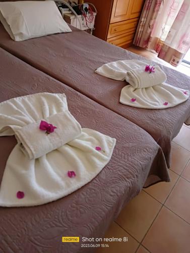 two beds with white towels and pink flowers on them at Villa Filia in Almiros Beach