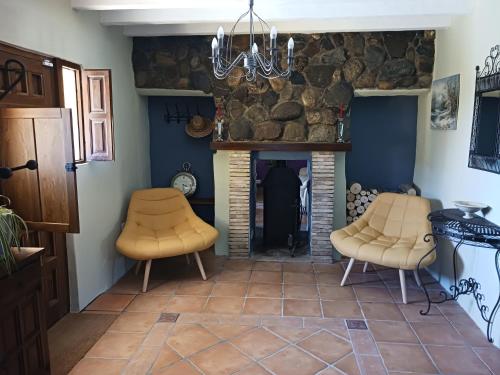 a living room with two chairs and a stone fireplace at Casa rural los Cerezos in Albox