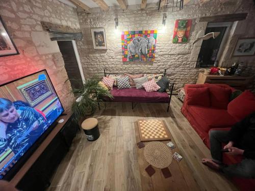 ein Wohnzimmer mit einem roten Sofa und einem TV in der Unterkunft Moonlight cottage france in Courchamps