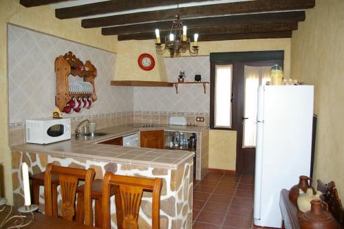 uma cozinha com um frigorífico branco, uma mesa e cadeiras em Casa Rural Cristina II em San Pablo de los Montes