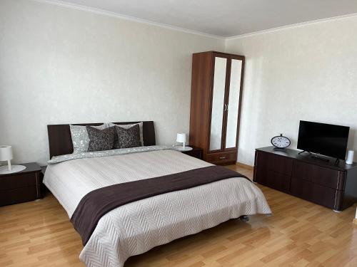 a bedroom with a large bed and a flat screen tv at Maxima apartments in Daugavpils