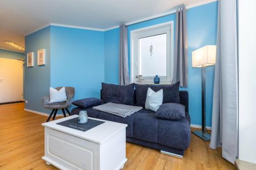 ein Wohnzimmer mit blauen Wänden und einem blauen Sofa in der Unterkunft Möwen-Butze 8103 Yachthafenresidenz in Kühlungsborn