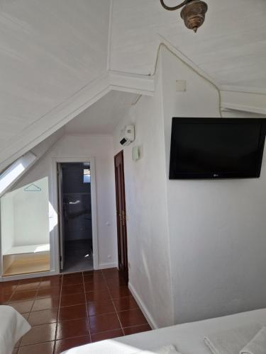 a bedroom with a flat screen tv on a wall at Casa do Miguel in Foz do Arelho