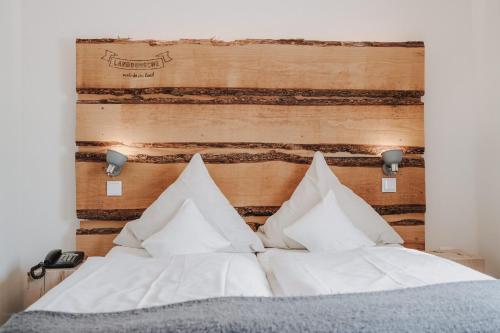 a bed with white pillows and a wooden headboard at Buchnas Landhotel Saarschleife in Mettlach