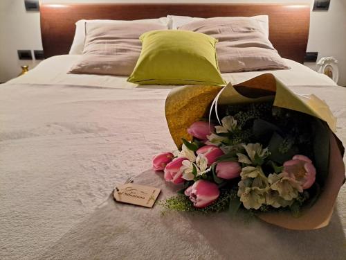 Al Nifontano B&B - Ideal for Family or Couples - 2 Rooms - Lakeview في فاريزي: حفنة من الزهور على سرير مع علامة عليه