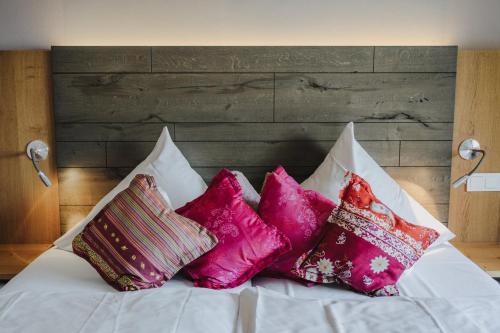a white bed with pink pillows on it at Buchnas Landhotel Saarschleife in Mettlach