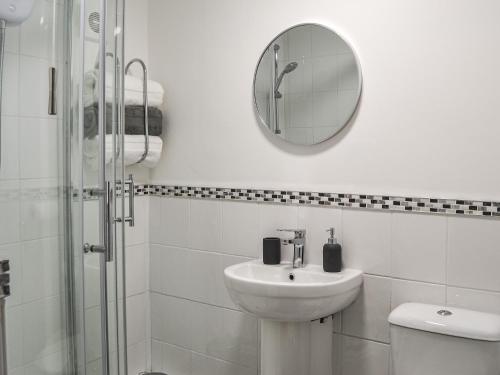 a white bathroom with a sink and a mirror at Hogarth Apartment By The Sea in Newbiggin-by-the-Sea