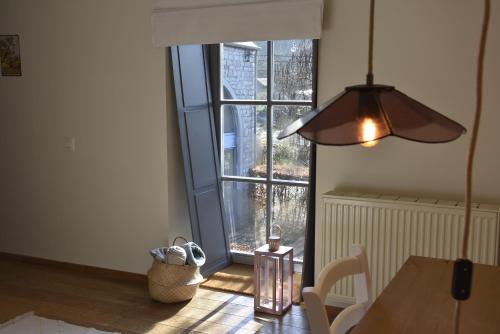 a dining room with a table and a large window at La Colline aux Fées in Yvoir