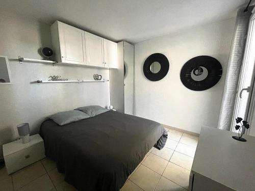 une chambre avec un lit et une horloge au mur dans l'établissement Appart CLIM , WIFI, PLAGE 200 mètres, à Argelès-sur-Mer