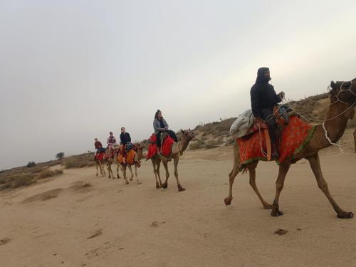 un grupo de personas montando camellos en el desierto en Ideal Guest House en Jaisalmer
