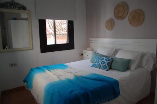 1 dormitorio con cama con sábanas azules y ventana en Markesa, en Plasencia