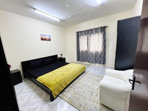 a bedroom with a black bed and a yellow blanket at Sam Home in Sharjah