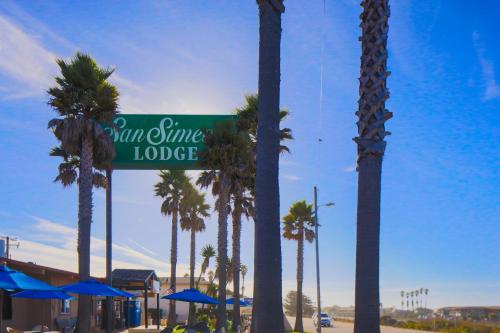 a street sign that reads sun shine lodge with palm trees at San Simeon Lodge in San Simeon