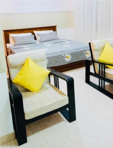 JJ Homestay في نيجومبو: غرفة نوم بسرير وكرسي مع وسادة صفراء