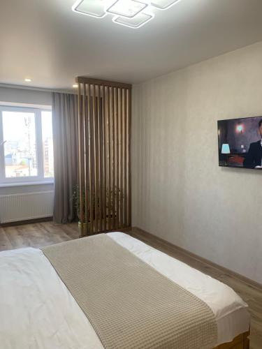 a bedroom with a bed with a tv on the wall at Dream town Apartaments біля залізничного вокзалу in Luts'k